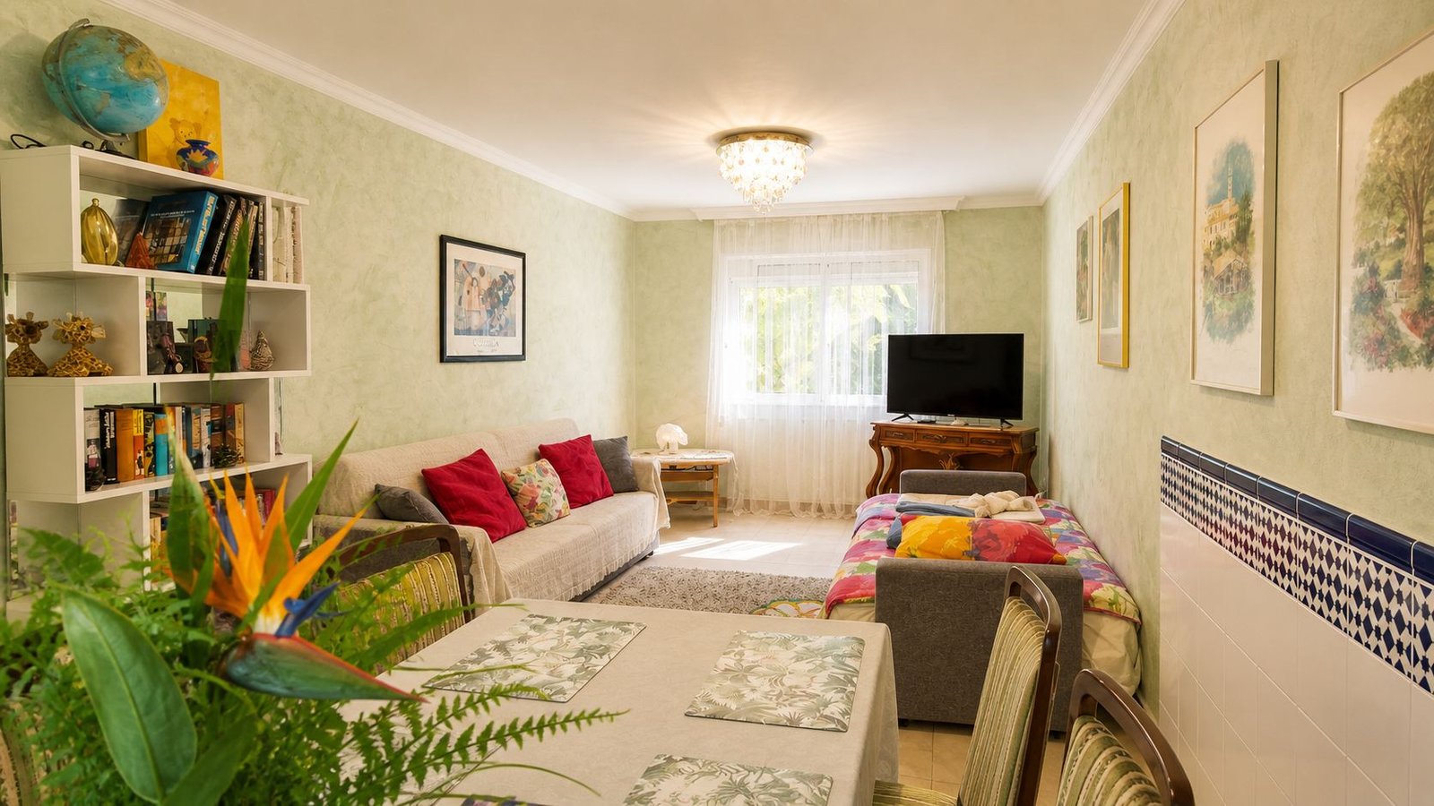 Salon et salle à manger lumineux dans l'appartement familial, équipés d'un canapé, d'un lit d'appoint et d'une télévision